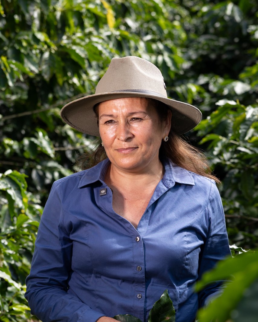 Maira Lizzeth Gómez Meza standing among her coffee plants in Honduras