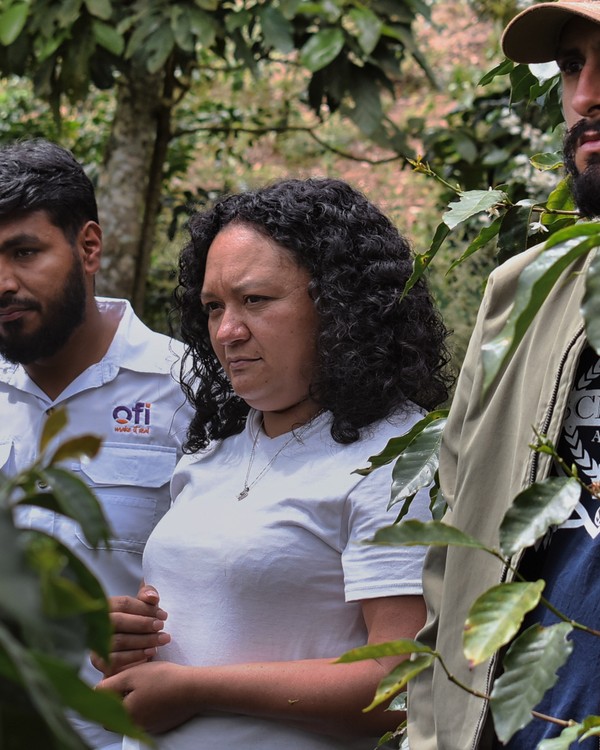Dania Liseth Alvarenga among coffee trees on the farm with two colleagues