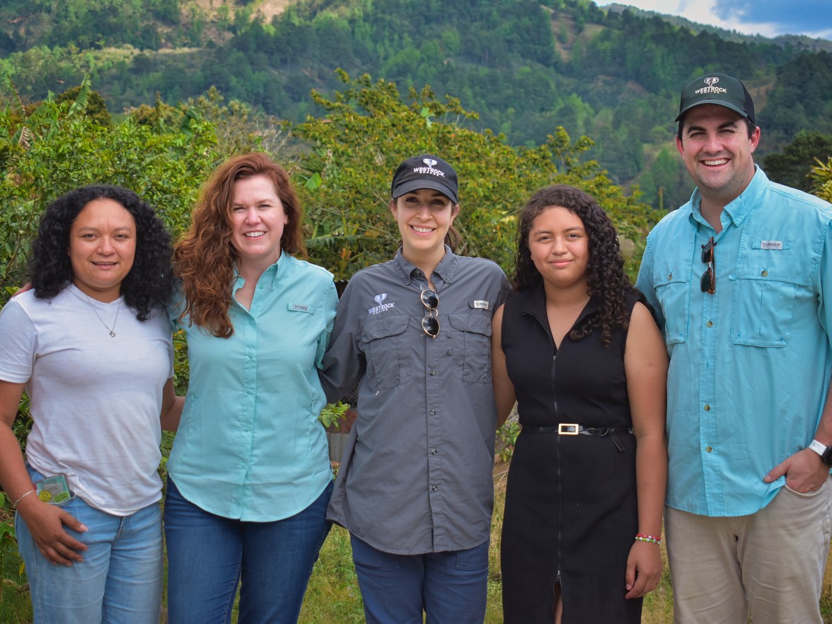 Dania, left, with visitors from Westrock Coffee in front of green hills